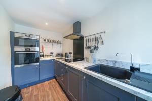 a large kitchen with blue cabinets and a sink at Library View Apartment in Kendal