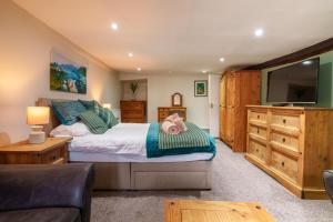 a bedroom with a bed and a flat screen tv at Library View Apartment in Kendal