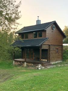 una gran casa de madera con techo en un campo en Liepų pirtis en Miežoniai