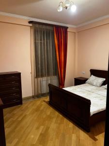 a bedroom with a bed and a dresser and a window at Home in Yerevan