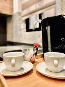 deux tasses sur des assiettes sur un comptoir avec une cafetière dans l'établissement Diamonds Luxury Apartments, à Marsalforn