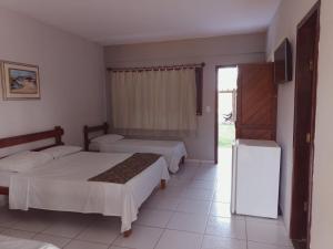 1 dormitorio con 2 camas, TV y nevera en Pousada Cheiro de Mar, en Nova Viçosa
