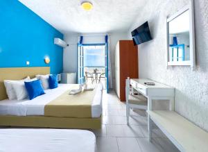 a hotel room with two beds and a desk and a window at Bluu Bahari Hotel in Karpathos