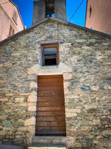 un edificio de ladrillo con puerta y ventana en Nuits magiques au village entre mer et montagnes, en Bigorno