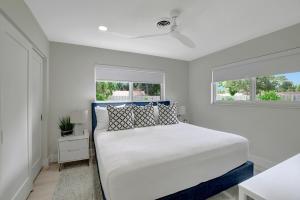 1 dormitorio blanco con 1 cama y 2 ventanas en Coastal Palms House, en Boynton Beach