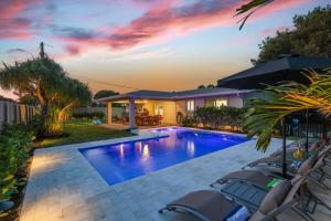 a swimming pool with chairs and a house at Coastal Palms House in Boynton Beach