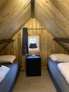 Cette chambre comprend deux lits et une lampe sur une table. dans l'établissement gezellige cottage in zeeland, à Sint-Annaland