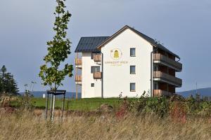 a white building on a hill with a tree at Apartmány Smrkový vrch in Vaclavov u Bruntalu