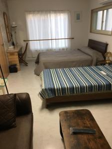 a living room with two beds and a couch at Accommodation Service B&B in Miyazaki