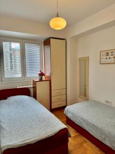 1 Schlafzimmer mit 2 Betten, einer Kommode und Fenstern in der Unterkunft Modern & Cozy in Skopje