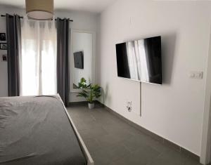 Habitación con TV de pantalla plana en la pared en Precioso piso con piscina, en Salobreña