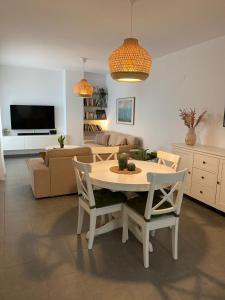 sala de estar con mesa, sillas y sofá en Precioso piso con piscina, en Salobreña