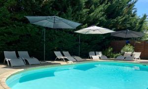 a swimming pool with umbrellas and chairs and a pool at Ô Clair de Lune Chambres d'hôtes climatisées à Sarlat - parking privé - piscine chauffée - espace bien-être Jacuzzi et massages in Sarlat-la-Canéda