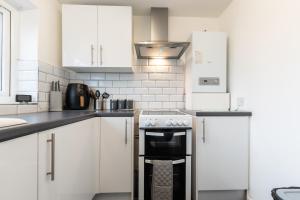 a kitchen with white cabinets and a black oven at NEW - Central Modern Flat in Southampton, Sleeps 5, Free Off-Road Parking, Close to Hospital, Cruise terminal and Centre, Great for contractors, friends & families in Southampton