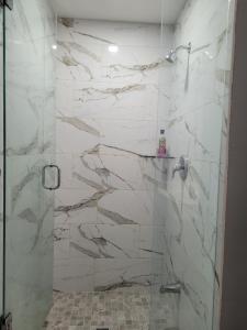 um chuveiro com paredes de mármore branco e uma porta de vidro em Individual home em Brampton