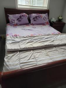 an unmade bed with purple pillows and purple sheets at Individual home in Brampton