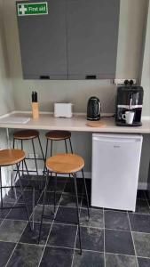 a kitchen with three bar stools and a counter at Rotherham Kimberworth home from home with WIFi and Driveway in Kimberworth