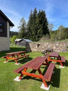 three picnic tables in the grass near a stone wall at Chata Polka in Horní Vltavice
