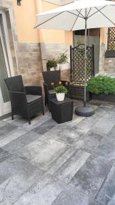 a patio with chairs and an umbrella and plants at Casetta Nilu' in Procida