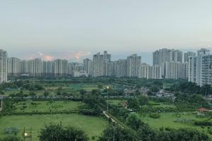 a park in a city with tall buildings at Chic Apartment#Couple Goal#High Rise#Balcony#condo in Noida +9 photos