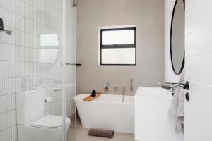 a bathroom with a tub and a toilet and a sink at Uitwaaien Beach Cottage in Pearly Beach +24 photos