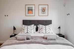 a bedroom with a large white bed with pillows at Uitwaaien Beach Cottage in Pearly Beach