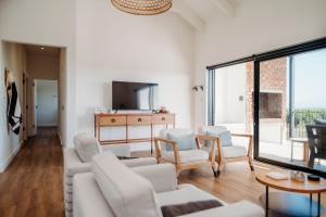 a living room with white furniture and large windows at Uitwaaien Beach Cottage in Pearly Beach