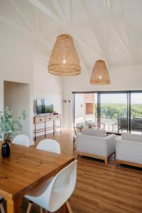 a living room with a wooden table and white chairs at Uitwaaien Beach Cottage in Pearly Beach