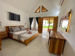 a bedroom with a bed and a table and a window at Abdi Fantastik in Gili Air