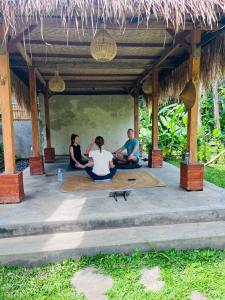 a group of people sitting on the floor under a pavilion at Yasa Backpackers house in Ubud