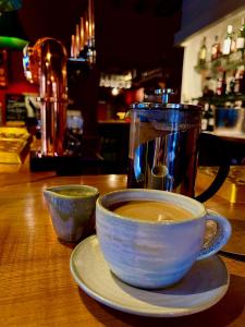 uma chávena de café sentada numa mesa com um bule de chá em Five Alls em Lechlade