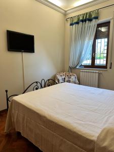 een slaapkamer met een bed, een stoel en een televisie bij VerdeMareVilla in Avola