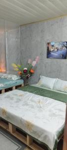 1 dormitorio con 2 camas y un jarrón de flores en H2_Homestay phố cổ _Check in tự động, en Hanói