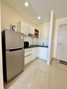 una cocina con nevera de acero inoxidable y armarios blancos en Chez Wanida - apartment Krabi, en Klong Muang Beach