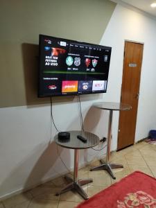 a flat screen tv hanging on a wall with a table at Pousada Indi in Ribeirão Preto