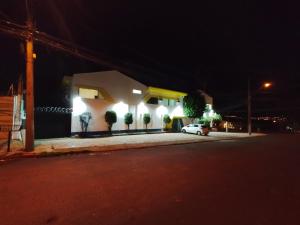 ein weißes Auto, das nachts vor einem Gebäude parkt in der Unterkunft Pousada Indi in Ribeirão Preto