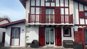uma casa com portas vermelhas e uma varanda em Location appartement dans Maison Basque em Urcuit