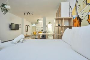 a bedroom with a white bed with a painting on the wall at Ran's BIG Artistic Studio in Tel Aviv