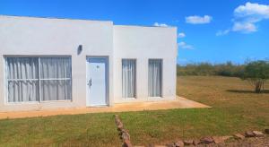 a white building with two doors and a field at INGA in Ituzaingó