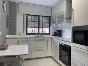a kitchen with white cabinets and a sink and a window at Alojamiento Alameda in Redondela