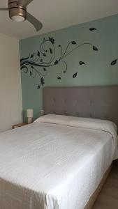 a bedroom with a white bed with a flower pattern on the wall at Enjoy Morro Jable in Morro del Jable