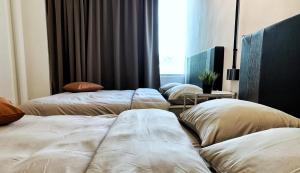 três camas alinhadas num quarto com uma janela em City Center w/ Home Cinema @The 5000 studio em Kuala Terengganu