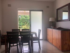 Un comedor con mesa y sillas y una ventana. en One Oban Place in Sunwich Port, en Port Shepstone