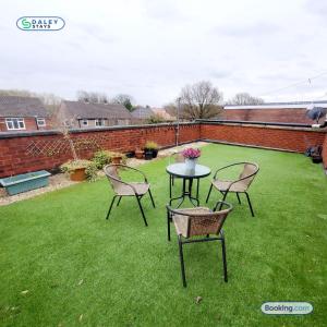 a patio with a table and chairs on a lawn at Cheadle Rooftop Apartment by Daley Stays - Sleep 6 in Cheadle Hulme
