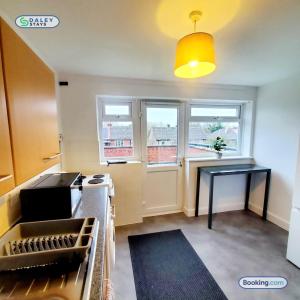 a kitchen with a counter and a table and windows at Cheadle Rooftop Apartment by Daley Stays - Sleep 6 in Cheadle Hulme