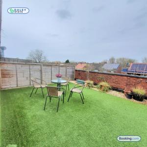 a patio with a table and chairs on the grass at Cheadle Rooftop Apartment by Daley Stays - Sleep 6 in Cheadle Hulme