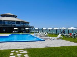 a swimming pool with lounge chairs and the ocean in the background at ili ili Hotel Boutique in Mar del Plata