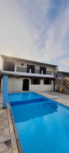 une grande piscine bleue devant une maison dans l'établissement casa do fred enseada, à Guarujá