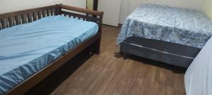 1 dormitorio con 2 camas y suelo de madera en casa do fred, en Guarujá