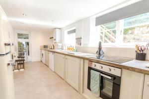 a large kitchen with white cabinets and a large window at Jaw-dropping view over the English Channel in Wroxall